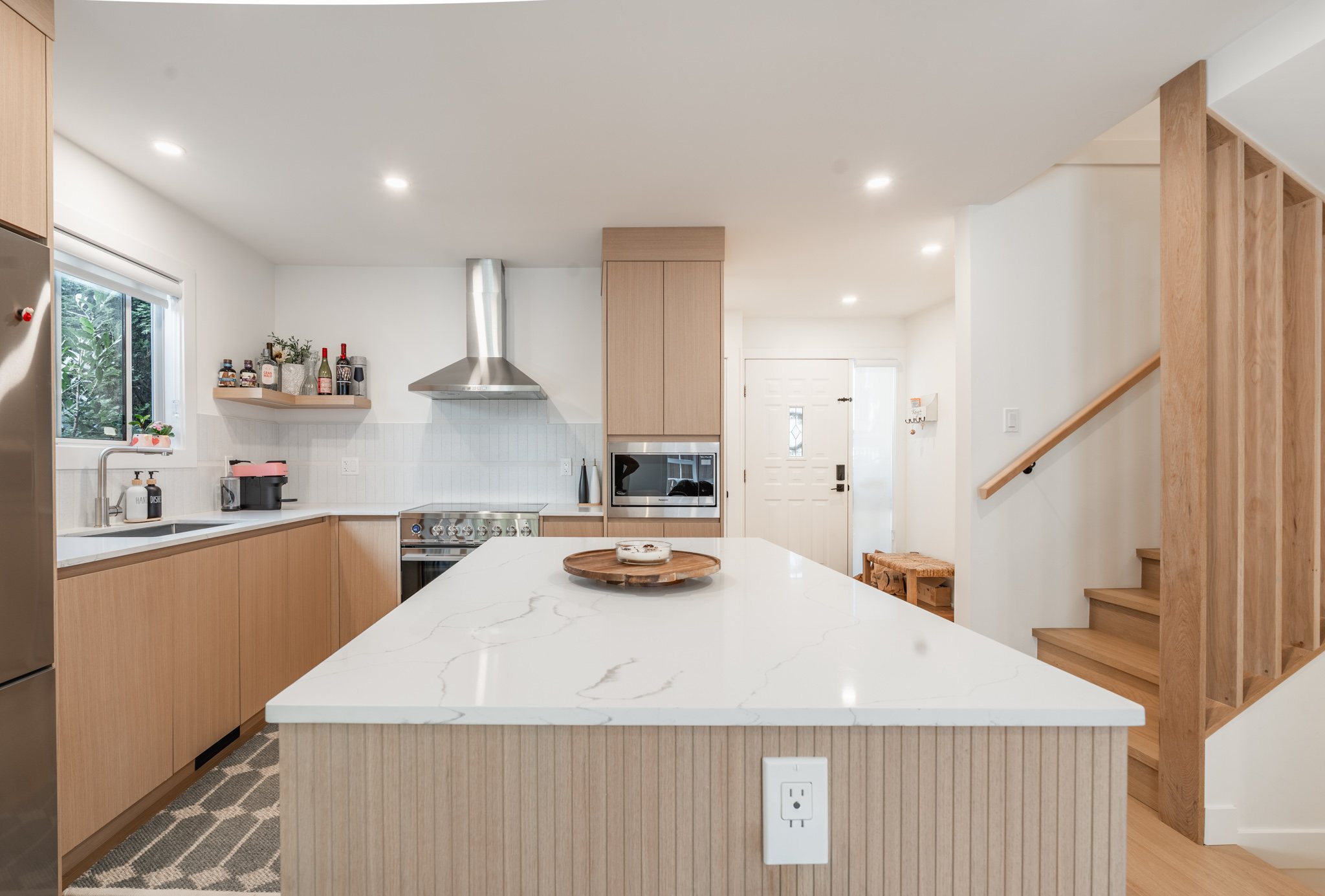 Contemporary kitchen with warm wood cabinetry and a large waterfall island
