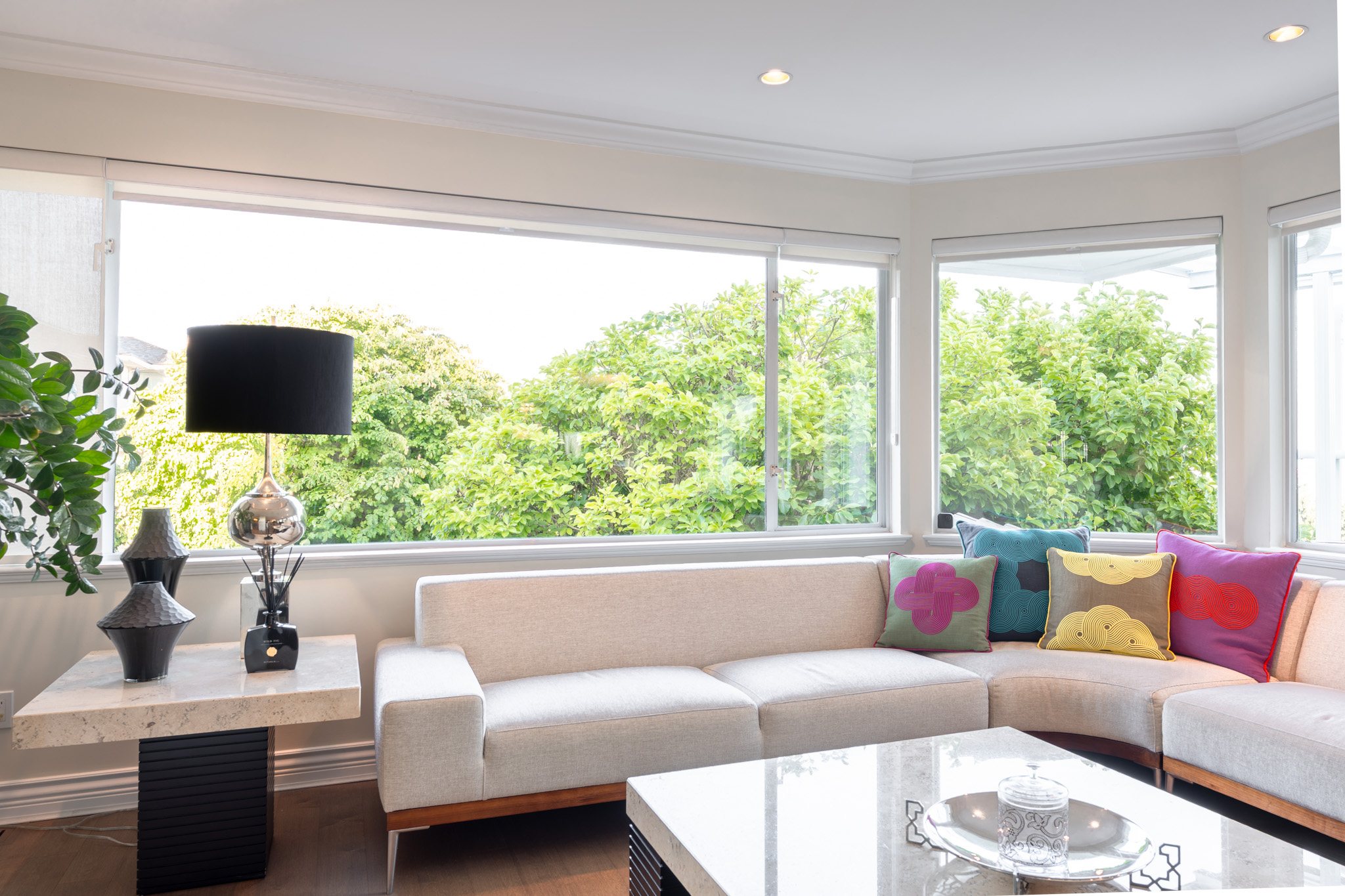 Sunlit living room framed by broad windows and garden views
